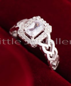A stunning silver ring with a radiant cut stone in the center and smaller hearts on either side that say 