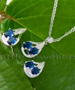 This exquisite piece of jewelry features a magnificent blue gem set in high-quality silver. The gem is flawlessly complemented by a pair of exquisitely crafted earrings and a delicate silver chain.